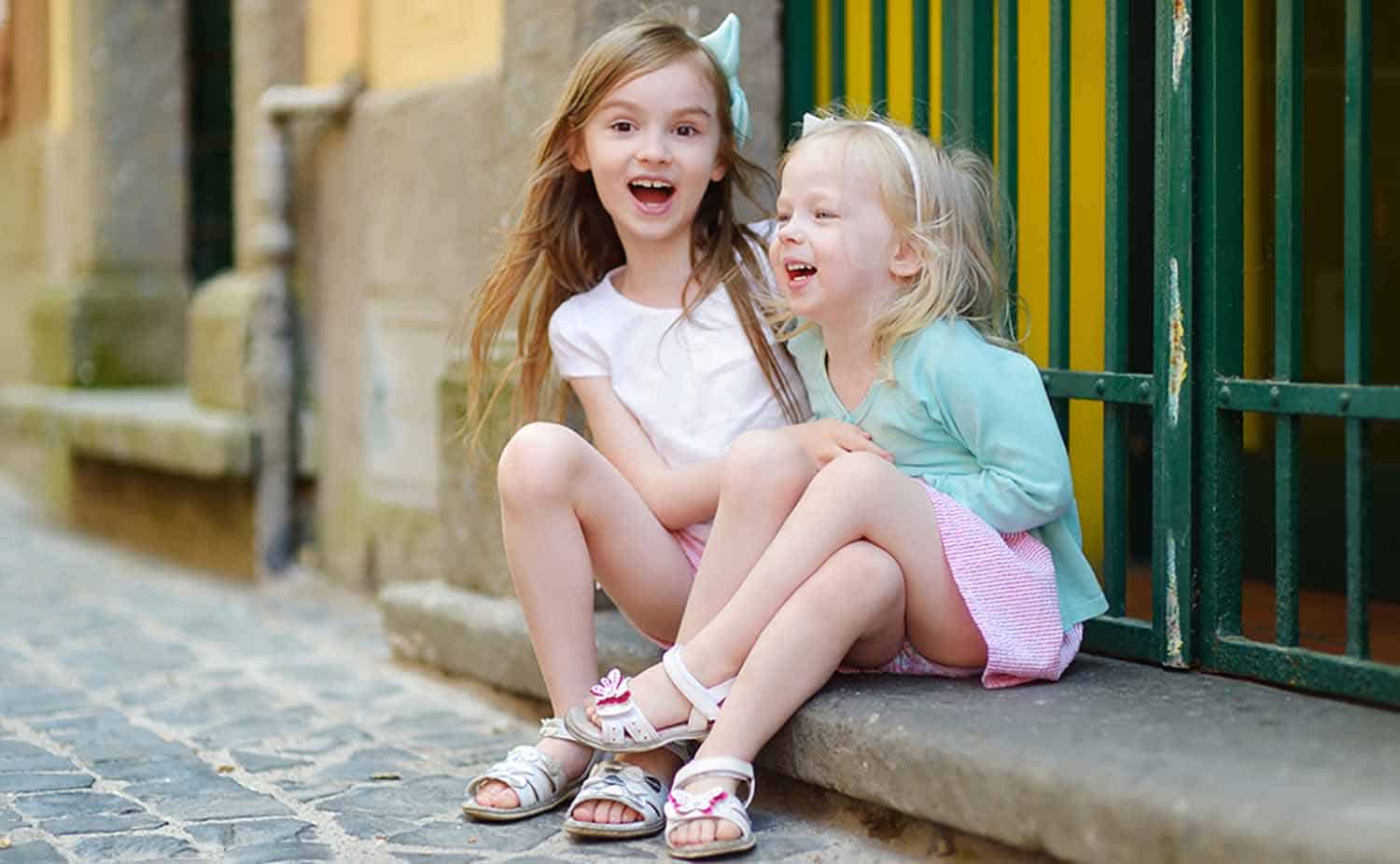 Two children laughing on the steps not worrying about head lice