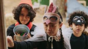 three children wearing halloween costumes and knocking on a door while trick or treating